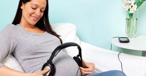 Pregnant woman playing music to her baby through headphones