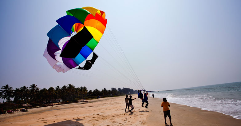 Tourists parasailing on a beach, North Goa, Goa, India Tourists parasailing on a beach, North Goa, Goa, India