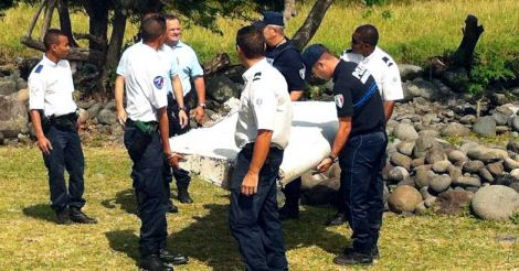 Police carry a piece of debris from an unidentified aircraft found off the coast of Reunion island.