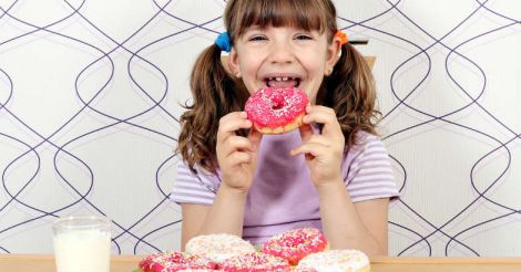 Happy little girl eating donuts