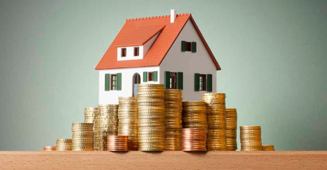 547451008 Miniature model house standing on a stack of coins.