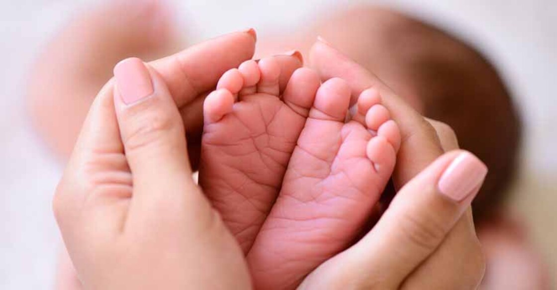 Mother holding tiny foot of newborn baby