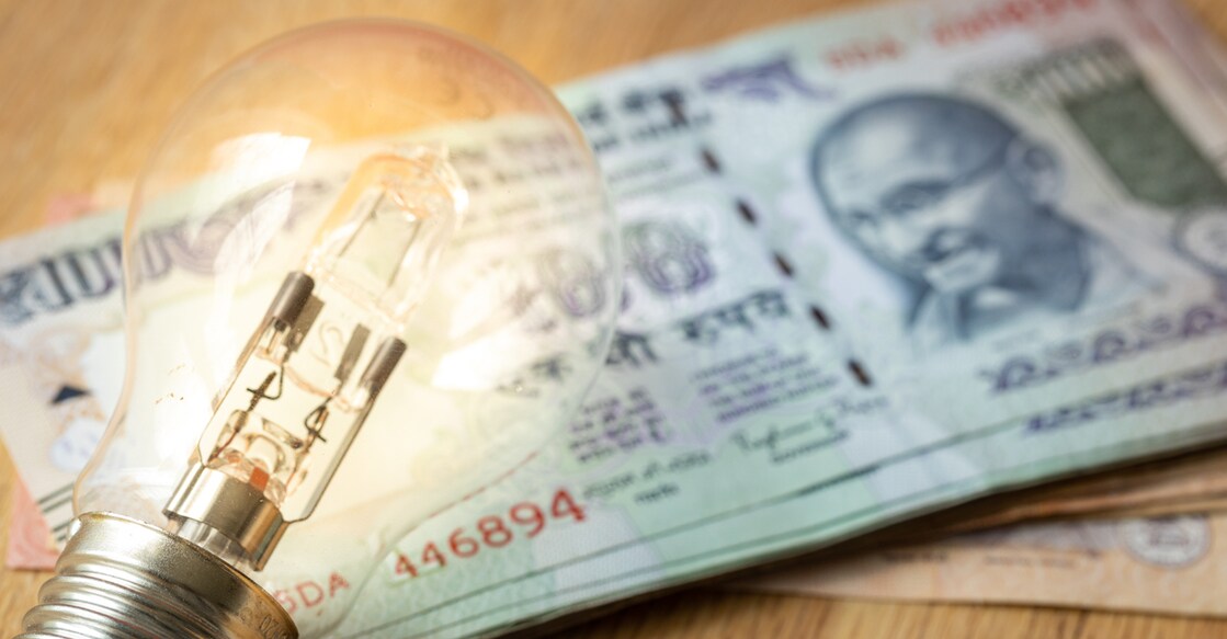 Indian money Lots of rupees and a light bulb, concept of rising energy and electricity prices in India
