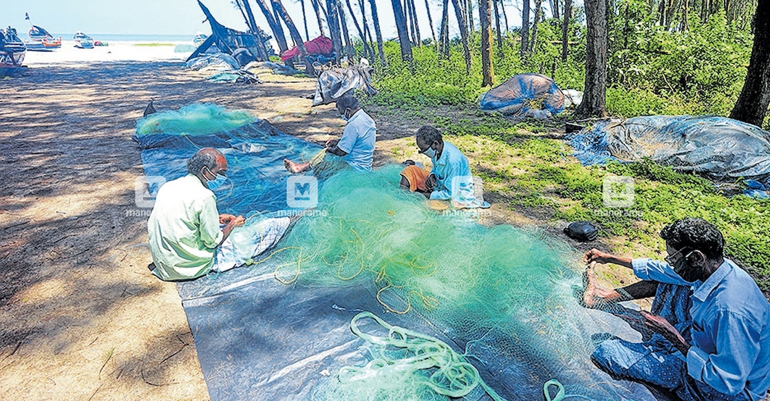 കോവിഡ് നിയന്ത്രണങ്ങളുടെ ഭാഗമായി മത്സ്യബന്ധനം നിരോധിച്ചിരിക്കുന്നതിനാൽ കടലിൽ പോകാതെ തീരത്ത് വല നന്നാക്കുന്ന മത്സ്യത്തൊഴിലാളികൾ. ആലപ്പുഴ വാടയ്ക്കൽ കടപ്പുറത്ത് നിന്നുള്ള കാഴ്ച. ട്രോളിങ് നിരോധനം അവസാനിച്ചെങ്കിലും കോവിഡ് നിയന്ത്രണങ്ങൾ മൂലം കടലിൽ പോകാൻ കഴിയാത്ത അവസ്ഥയിലാണ് മത്സ്യത്തൊഴിലാളികൾ.  ചിത്രം: മനോരമ