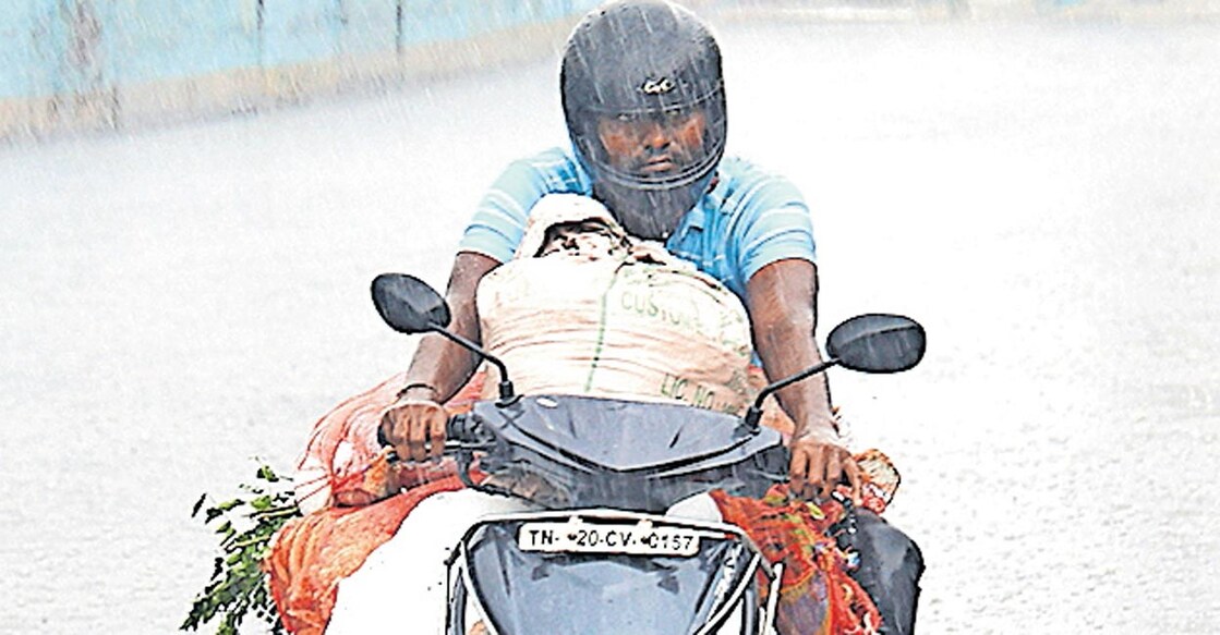 അപ്രതീക്ഷിതമായി പെയ്ത വേനൽ മഴയിൽ നനഞ്ഞ് യാത്ര ചെയ്യുന്ന ആൾ. തുരൈപ്പാക്കത്തു നിന്നുള്ള കാഴ്ച.  
