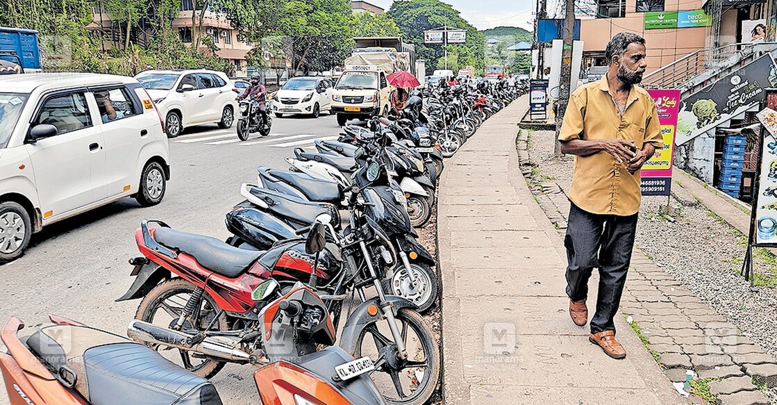 കളമശേരി എച്ച്എംടി ജംക്‌‌ഷനിൽ വ്യാപാര സ്ഥാപനങ്ങളുടെ മുൻഭാഗത്തെ പാർക്കിങ് സൗകര്യം ഉപയോഗപ്പെടുത്താൻ കഴിയാത്ത വിധം പൊതുമരാമത്ത് വകുപ്പ് റോഡിൽ ഉയർത്തി നി‍ർമിച്ചിട്ടുള്ള കാനയും റോഡിൽ പാർക്ക് ചെയ്തിട്ടുള്ള ഇരുചക്ര വാഹനങ്ങളും.  
