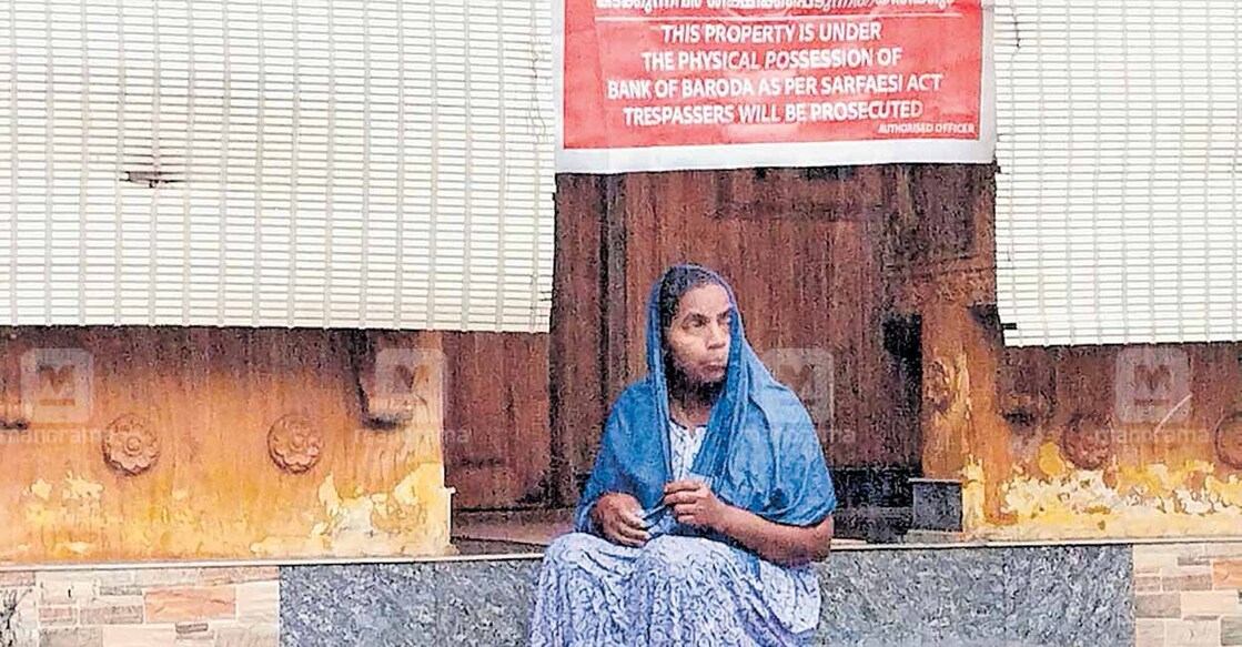 ബാങ്കുകാർ ജപ്തി ചെയ്ത് ബോർഡ് സ്ഥാപിച്ച വീടിന്റെ പടിക്കെട്ടിൽ ഓമന  

