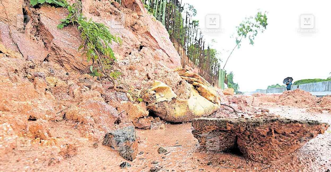 കനത്ത മഴയിൽ എടക്കാട് റെയിൽവേ സ്റ്റേഷനു സമീപം ഭൂതത്താൻകുന്നിന്റെ ഒരുഭാഗം ഇടിഞ്ഞ് സർവീസ് റോഡിലേക്ക് കല്ലും മണ്ണും  ഒലിച്ചെത്തിയ നിലയിൽ.  ചിത്രം: മനോരമ  