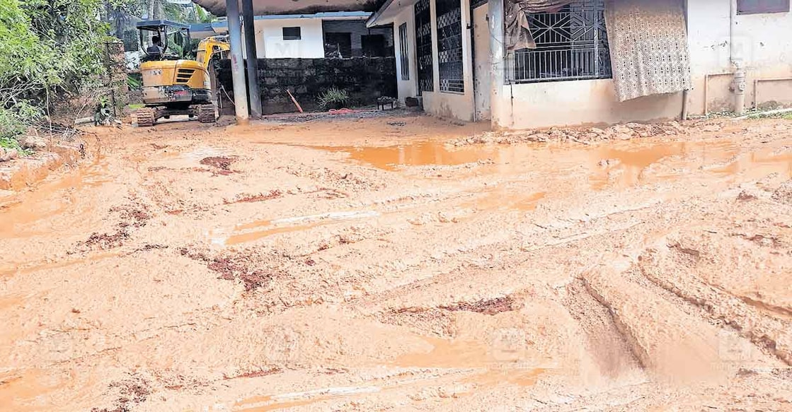 കുപ്പം സിഎച്ച് നഗറിലെ പി.വി.കുഞ്ഞാമിനയുടെ വീടിനു മുൻപിൽ കഴിഞ്ഞ ദിവസവും ചെളി കെട്ടിക്കിടക്കുന്ന നിലയിൽ. ദേശീയപാത നിർമാണ കമ്പനിയുടെ മണ്ണുമാന്തിയന്ത്രം ചെളി നീക്കം ചെയ്യുന്നതും കാണാം.  
