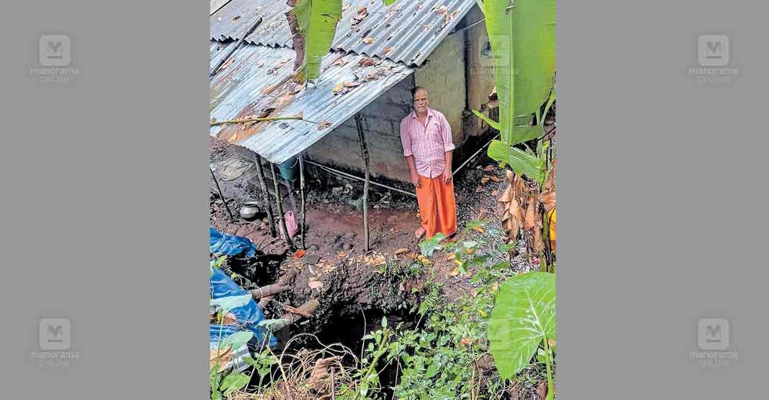 കൊളപ്പുറത്തെ കരുണാകരൻ നായർ തന്റെ വീടിനുപിന്നിലെ ഗർത്തത്തിനരികെ.