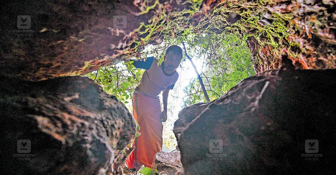 കൊളത്തൂർ മടന്തക്കോട് പുലി കുടുങ്ങിയ മാളം നോക്കിക്കാണുന്ന നാട്ടുകാരൻ. ചിത്രം: മനോരമ  