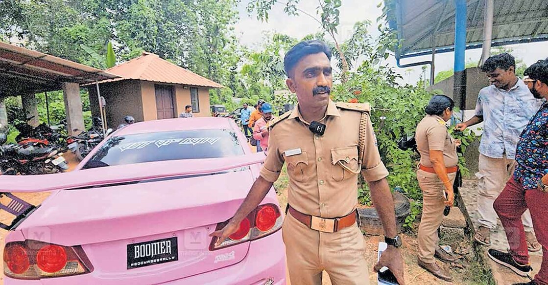 car-custody മോട്ടർ വാഹന വകുപ്പ് കസ്റ്റഡിയിലെടുത്ത കാറിന്റെ പിന്നിൽ നമ്പർ സ്ഥാപിക്കേണ്ട ഭാഗത്ത് ബൂമർ എന്നെഴുതിയത് ചൂണ്ടിക്കാട്ടുന്ന ഉദ്യോഗസ്ഥൻ