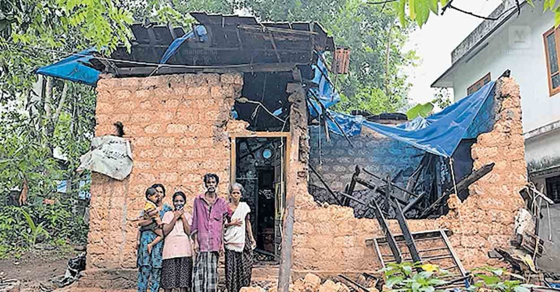 തകർന്ന വീടിനു മുന്നിൽ രാജേന്ദ്രൻ ആചാരിയും കുടുംബവും.  
