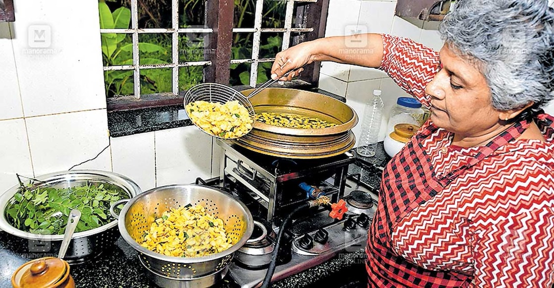 lathika-subash-house ലതിക സുഭാഷ് വീട്ടിലെ അടുക്കളയിൽ കായ ഉപ്പേരി വറുക്കുന്നു.