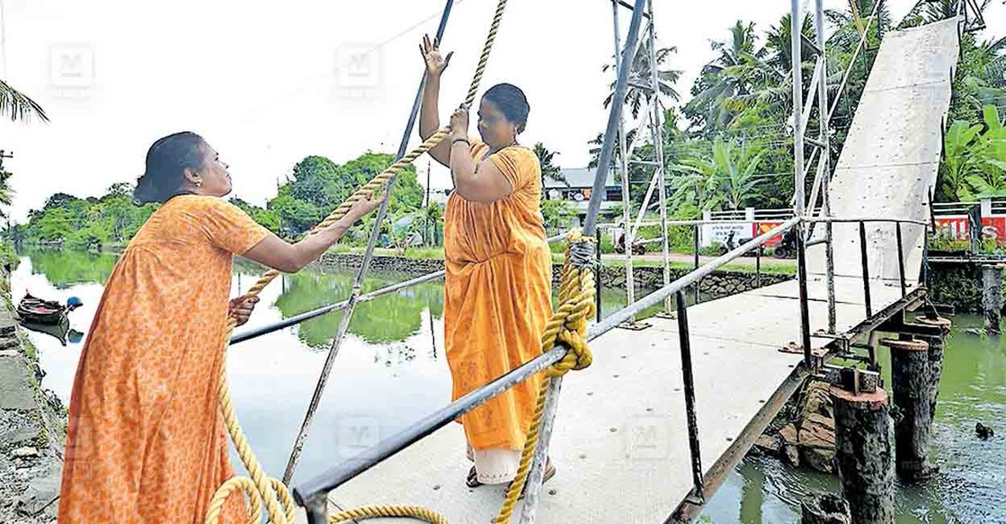 സുലജ സാബുവും ബന്ധു അനിലയും ചേർന്ന് ആലപ്പുഴ – കോട്ടയം ബോട്ട് കടത്തിവിടാനായി പാറേച്ചാൽ കയർ പാലം ഉയർത്തുന്നു. 
