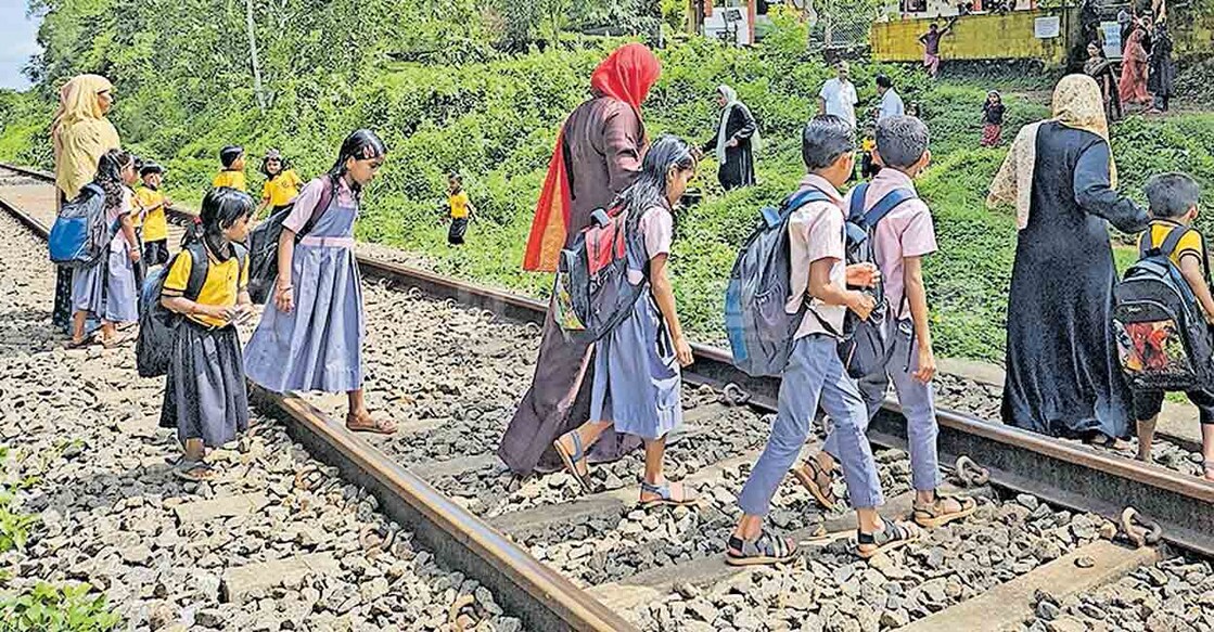 malappuram-thodikapulam-railway-problems മേൽപാലമില്ലാത്തതുകൊണ്ട് ഒറ്റപ്പെട്ടുപോയ തൊടികപ്പുലം എഎൽപി സ്കൂളിലെത്താൻ വിദ്യാർഥികളെ പാളം കടത്തുന്ന രക്ഷിതാക്കളും അധ്യാപകരും. മറുവശത്തു കാണുന്നതാണ് സ്കൂൾ.