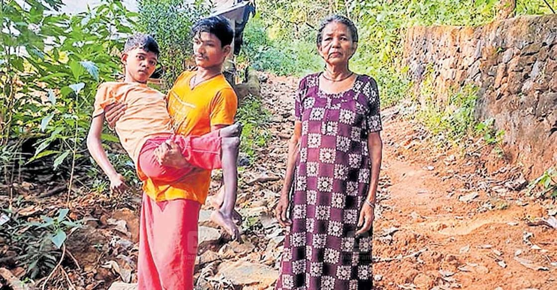 malappuram-unnikuttanl അരയ്ക്കുതാഴെ ചലന ശേഷിയില്ലാത്ത അമ്മിനിക്കാട് അത്തിക്കൽ മുള്ളൻമട ആദിവാസി കോളനിയിലെ ഉണ്ണിക്കുട്ടനെ വാരിയെടുത്ത് നിൽക്കുന്നത് ബന്ധുവാണ്. സമീപം ഉണ്ണിക്കുട്ടന്റെ വല്യമ്മ ശാന്ത.
