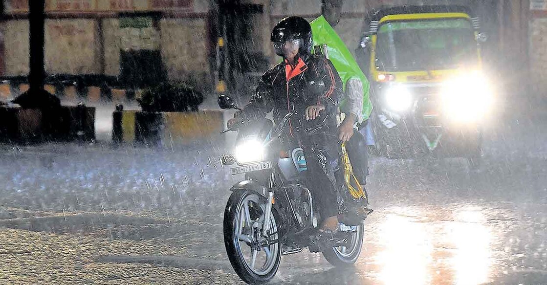 കനത്തചൂടിന് ആശ്വാസമായെത്തിയ മഴയിൽ നഗരത്തിലൂടെ യാത്ര ചെയ്യുന്നവർ. ചിത്രം: പിടിഐ