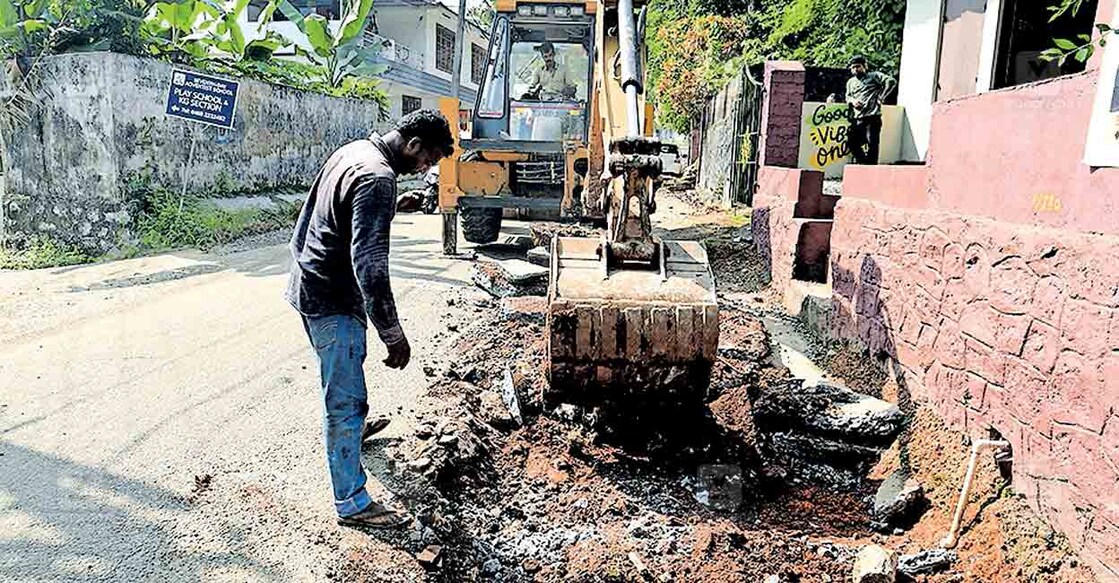 കോളജ് റോഡിരികിലെ കോൺക്രീറ്റ് മണ്ണുമാന്തി ഉപയോഗിച്ച് ഇളക്കുന്നു. ചിത്രം: മനോരമ  
