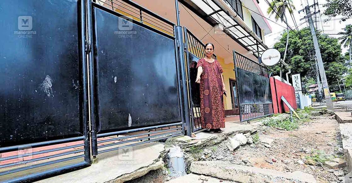 ശാസ്തമംഗലം–പേരൂർക്കട റോഡിനു സമീപത്തെ വീടിന്റെ മുൻഭാഗത്തുള്ള കുഴി ചൂണ്ടിക്കാണിക്കുന്ന ദീനാമ്മ ഏബ്രഹാം.ചിത്രം: മനോരമ  