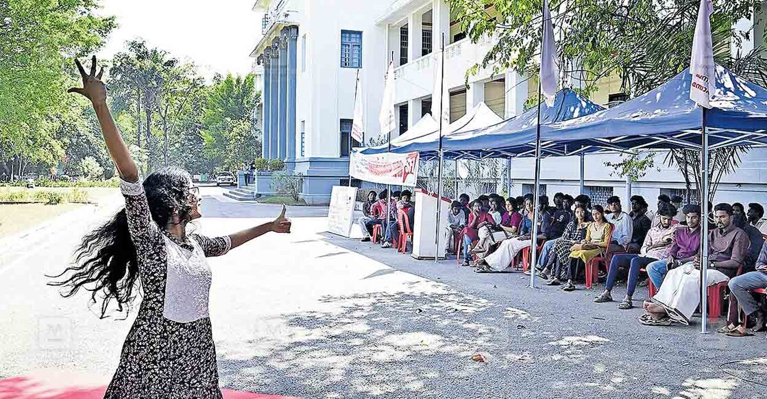 തിരഞ്ഞെടുപ്പ് കഴിഞ്ഞിട്ടും കേരള സർവകലാശാലാ യൂണിവേഴ്‌സിറ്റി യൂണിയൻ രൂപീകരിച്ച് വിജ്​ഞാപനം പുറപ്പെടുവിക്കാത്തതിൽ പ്രതിഷേധിച്ച് വാഴ്സിറ്റി ആസ്ഥാന വളപ്പിനുള്ളിൽ  എസ്എഫ്ഐ നടത്തുന്ന  പന്തൽ കെട്ടി സമരത്തിനു മുന്നിൽ സമരക്കാരിലൊരാളുടെ പ്രതിഷേധ നൃത്തം  ചിത്രം:  മനോരമ  

