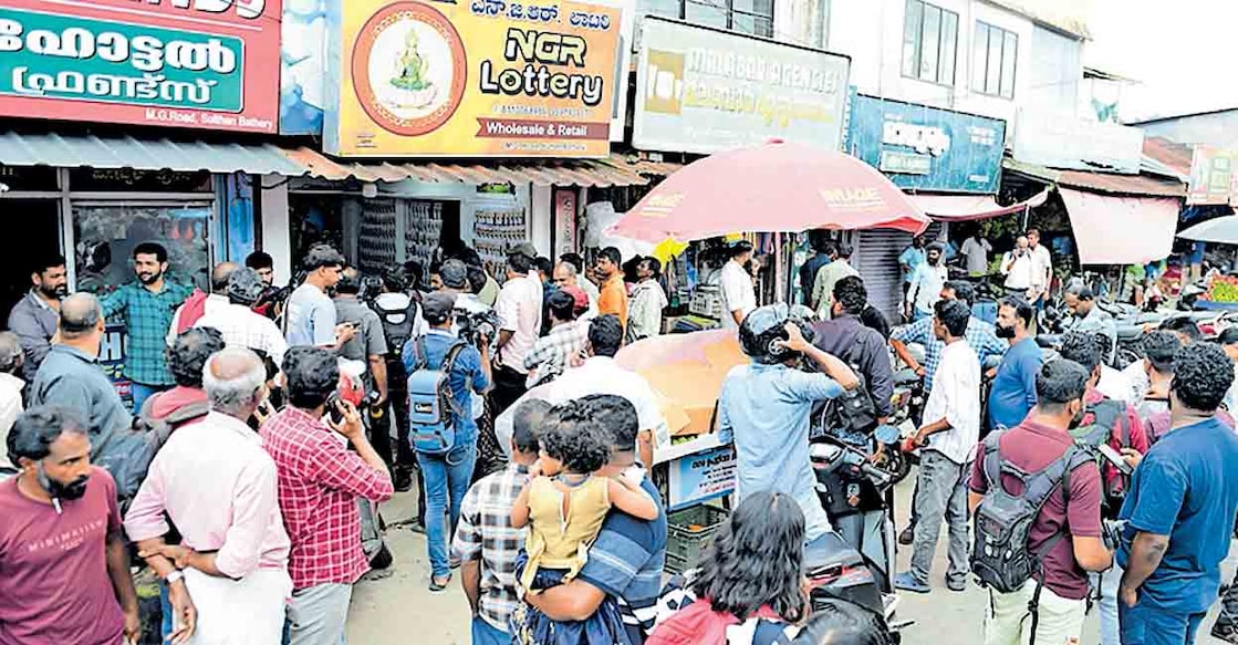 സംസ്ഥാന ഭാഗ്യക്കുറിയുടെ തിരുവോണം ബംപർ ഒന്നാം സമ്മാനം ലഭിച്ച ടിക്കറ്റ് വിൽപന നടത്തിയ ബത്തേരിയിലെ എൻജിആർ ലോട്ടറിക്കടയുടെ മുൻപിൽ തടിച്ചു കൂടിയവർ. ചിത്രം: മനോരമ  
