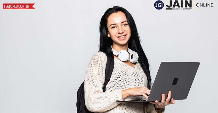 Happy young woman holding laptop and looking at camera over gray background Happy young woman holding laptop and looking at camera over gray background