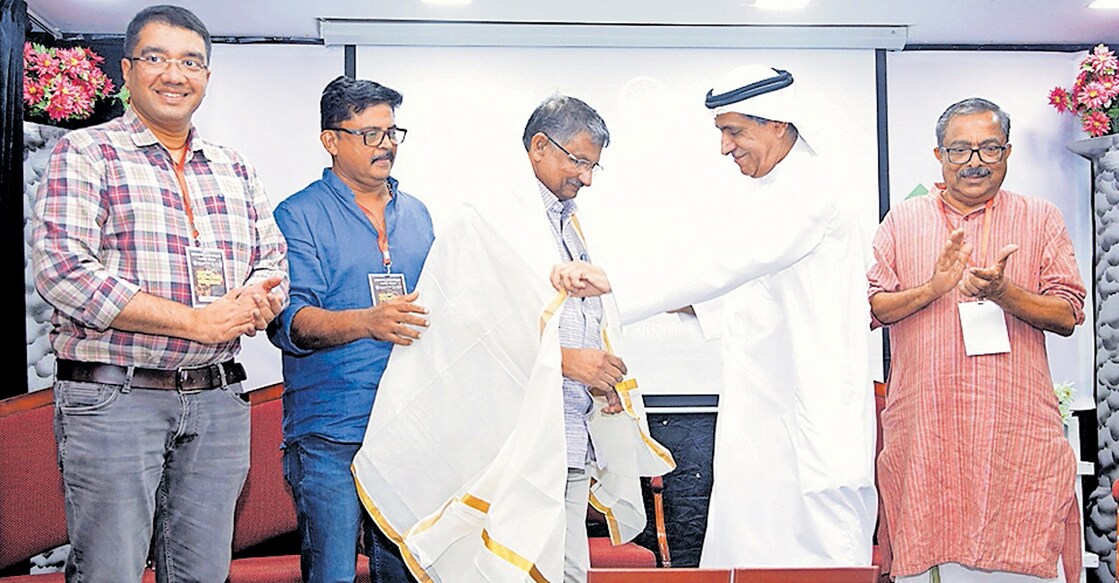abudhabi-kerala-social-center-organized-shilpashala വയലാർ അവാർഡ് നേടിയ അശോകൻ ചരുവിലിനെ അറബ് കവി ഖാലിദ് അൽ ബദൂർ പൊന്നാട അണിയിക്കുന്നു.