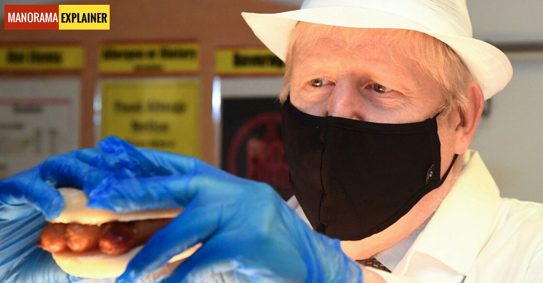 Boris Johnson | Sausage War | (Photo by Jeremy Selwyn / POOL / AFP) ബോറിസ് ജോൺസൺ സോസേജുമായി. (Photo by Jeremy Selwyn / POOL / AFP)