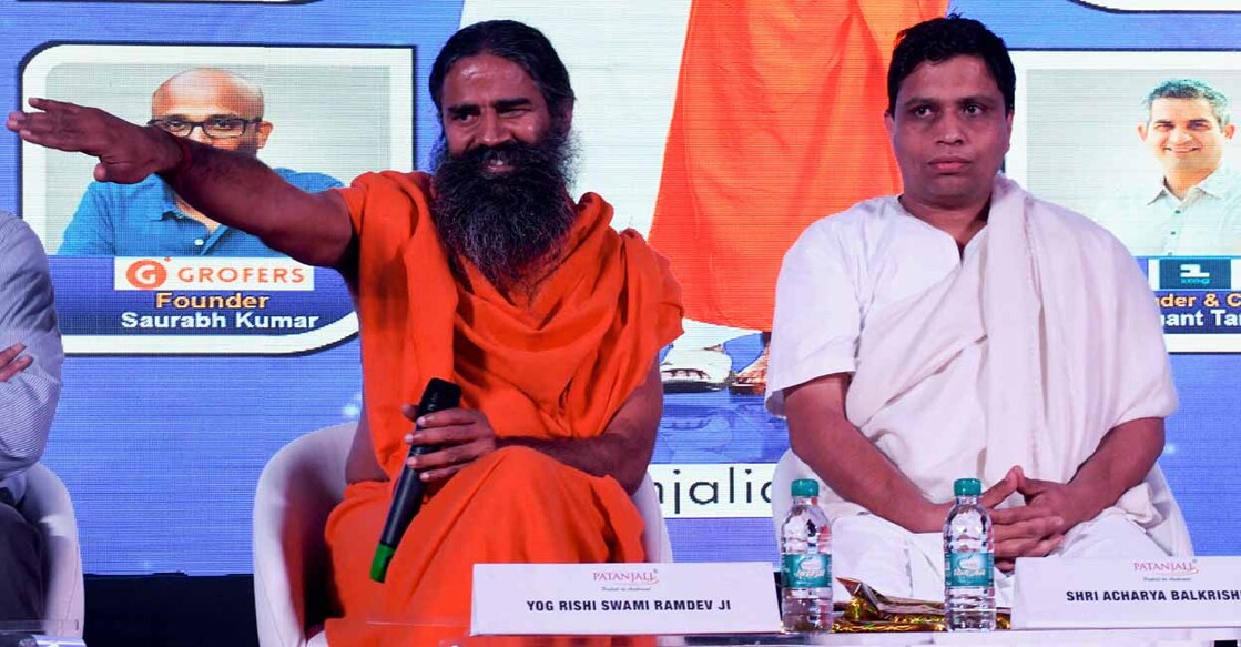 Indian yoga guru Baba Ramdev (L) and Patanjali Ayurveda Managing Director Acharya Balkrishna, during a press conference in New Delhi on January 16, 2018. - India's hugely popular yoga guru on January 16 announced a tie-up of his Patanjali brand with a clutch of e-commerce majors including Amazon, eyeing a slice of the lucrative $1 billion online market for consumer goods. (Photo by MONEY SHARMA / AFP)