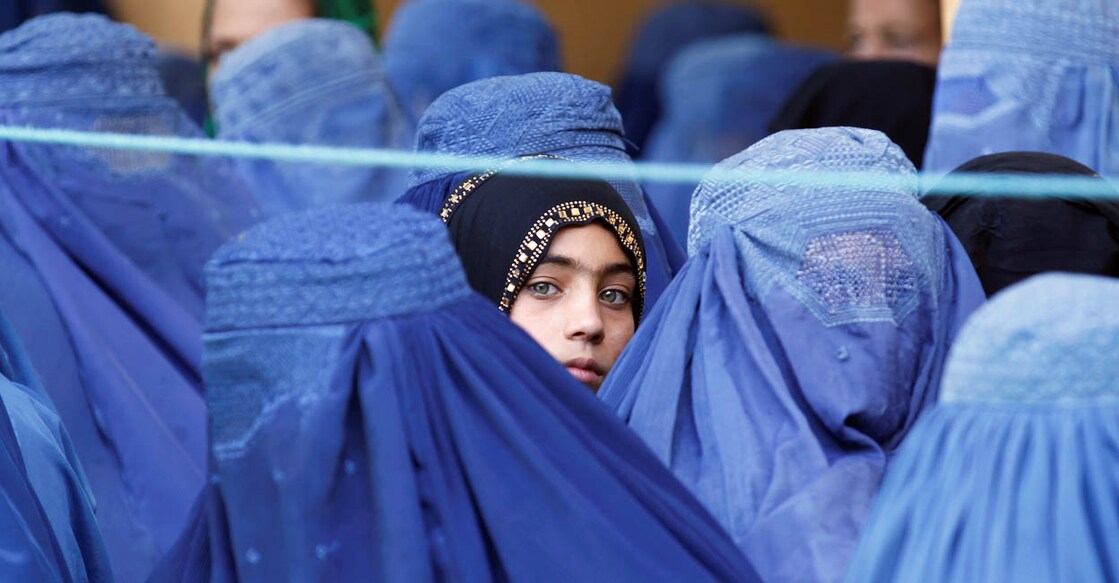 Afghan Woman അഫ്ഗാനിലെ ജലാലാബാദിൽ ഭക്ഷ്യസഹായം തേടിയെത്തിയ അഫ്ഗാൻ വനിതകൾക്കിടയിൽ നിൽക്കുന്ന പെൺകുട്ടി. 2017 ജൂലൈ 11 ന് പകർത്തിയ ചിത്രം – REUTERS/Parwiz