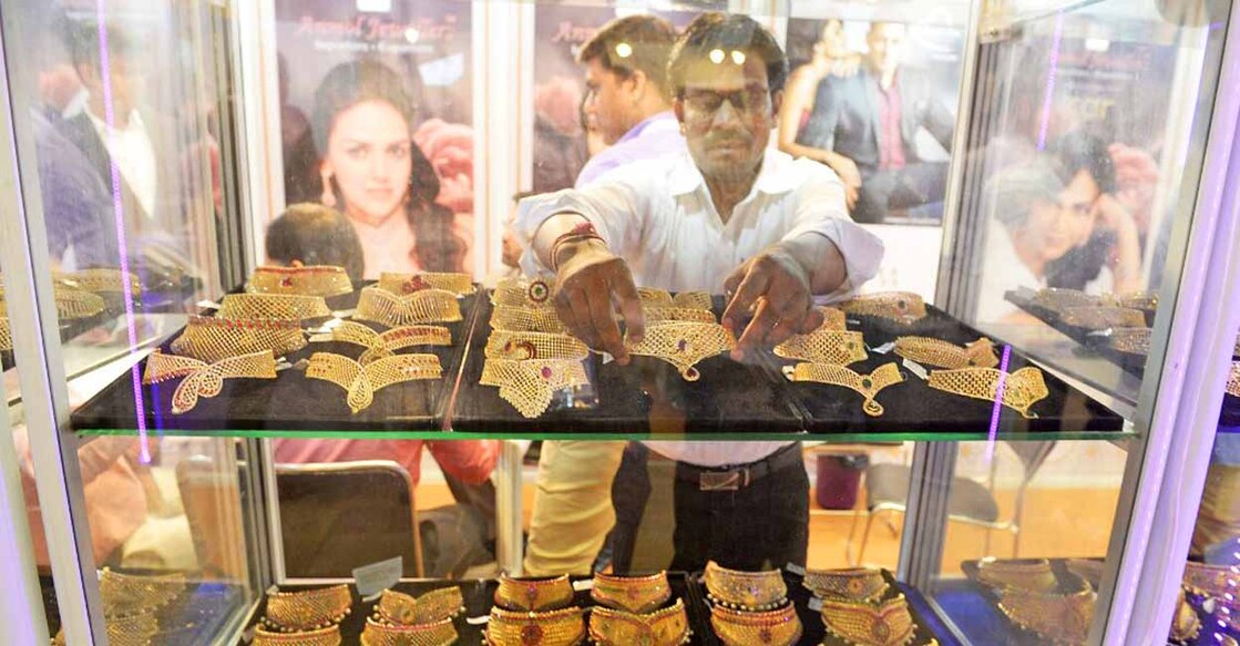 An Indian trader displays gold jewellery and ornaments during the Hyderabad Jewellery Pearl and Gem Fair (HJF) in Hyderabad on June 9, 2017. (Photo by NOAH SEELAM / AFP)