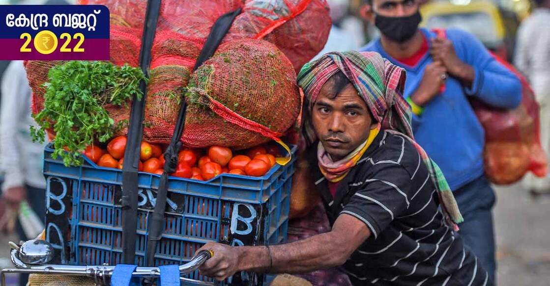 A daily wage worker carries sacks of vegetables on a bicycle during early morning in Mumbai on February 1, 2022. (Photo by Punit PARANJPE / AFP)