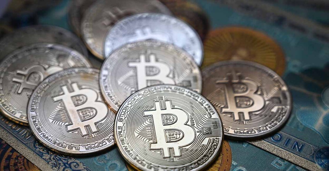 TURKEY-ECONOMY-MARKETS-CURRENCY-BITCOIN This illustration photograph taken on July 19, 2021 in Istanbul shows a physical banknote and coin imitations of the Bitcoin crypto currency. (Photo by Ozan KOSE / AFP)