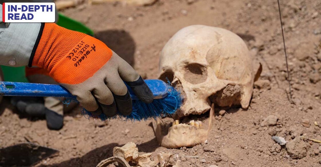 IRAQ-CONFLICT-GRAVES A forensics expert uses a brush to exhume a skull at the site of a mass grave, discovered by chance when property developers wanted to prepare the land for construction, in the central city of Najaf, on May 18, 2022. - The site in Najaf is one of many in a country that suffered through more than four decades of bloody conflict and turmoil. The years of violence have made Iraq one of the countries with the highest number of missing persons in the world, says the International Committee of the Red Cross. (Photo by Qassem al-KAABI / AFP)