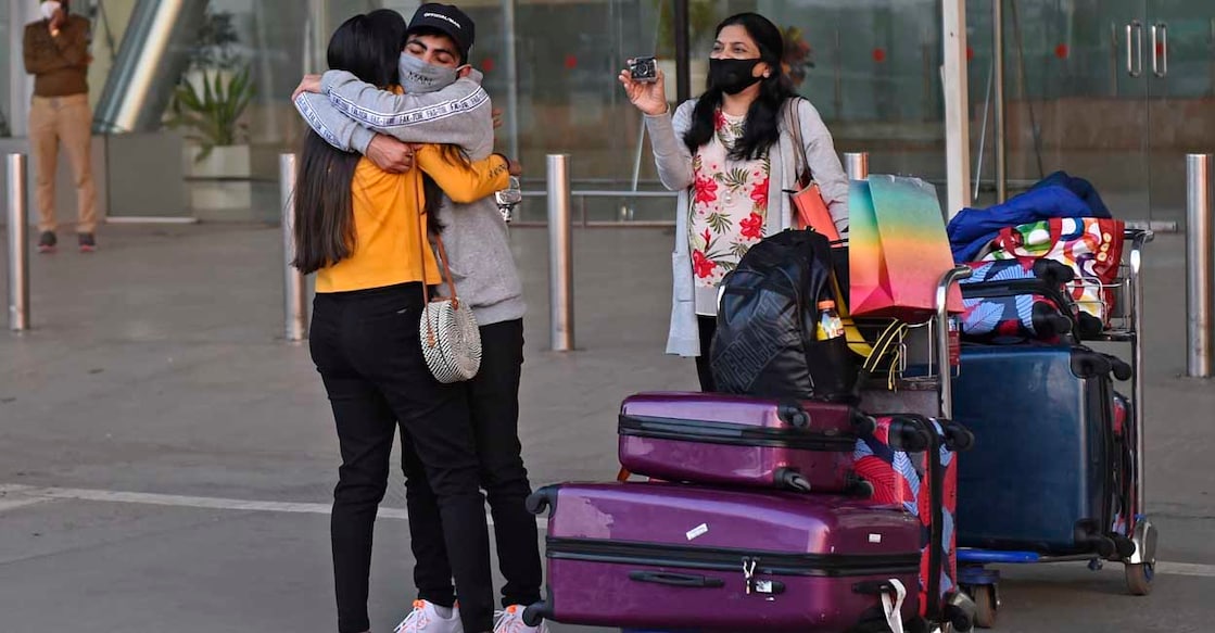Sardar Vallabhbhai Patel International Airport, Ahmedabad | (Photo by Sam PANTHAKY / AFP) കോവിഡ് കാലത്ത് യുകെയിൽനിന്ന് എത്തിയ യാത്രികനെ സ്വീകരിക്കുന്ന കുടുംബം. അഹമ്മദാബാദിലെ സർദാർ വല്ലഭായ് പട്ടേൽ രാജ്യാന്തര വിമാനത്താവളത്തിൽനിന്നുള്ള 2020 ഡിസംബർ 22ലെ ചിത്രം. (Photo by Sam PANTHAKY / AFP)
