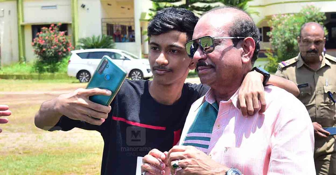 പുതുപ്പള്ളിയിൽ ഉമ്മൻചാണ്ടിയുടെ കുടുംബാംഗങ്ങളെ സന്ദർശിച്ച ശേഷം മടങ്ങുവാനായി ഹെലിപ്പാഡിൽ എത്തിയ എം.എ.യൂസഫലിയോടൊത്ത് സെൽഫി എടുക്കാൻ അനുവാദം ചോദിച്ച് എത്തിയതാണ് ഈ യുവാവ്. യൂസഫലി സമ്മതിച്ചപ്പോൾ തോളിൽ കയ്യിട്ടു സെൽഫിക്ക് പോസ് ചെയ്ത യുവാവിനെ സുരക്ഷാ ഉദ്യോഗസ്ഥർ തടഞ്ഞു. ''സ്നേഹത്തോടെ വച്ച കൈയല്ലേ ഇത് മാറ്റണ്ട '' എന്ന് പറഞ്ഞ് യൂസഫലി തിരിച്ച് തോളിൽ കൈയിടീച്ച് ഫോട്ടോയ്ക്ക് പോസ് ചെയ്യുന്നു. ചിത്രം: റിജോ ജോസഫ്∙ മനോരമ