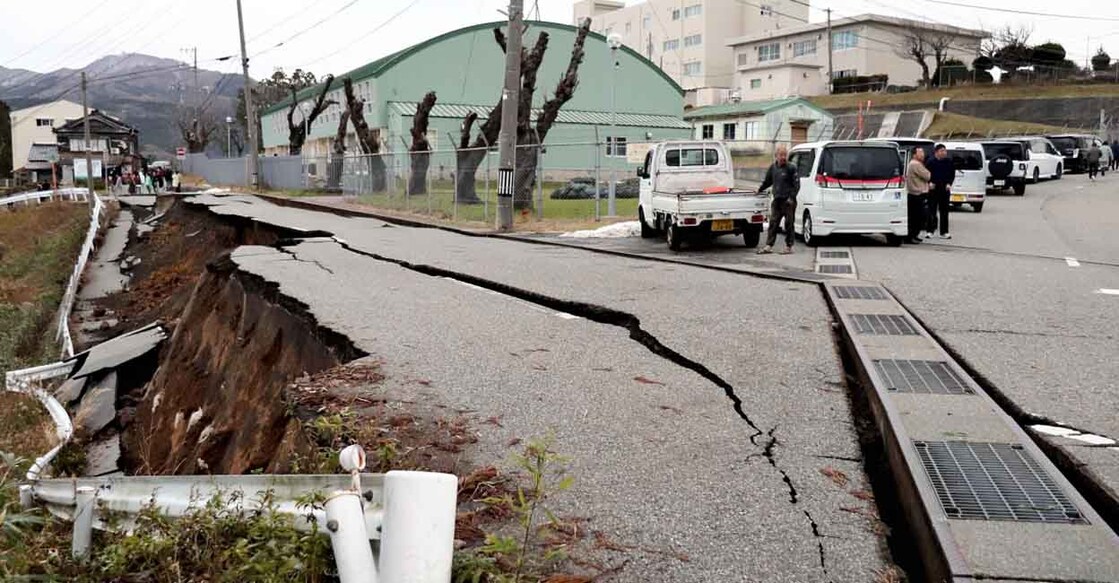 People stand next to large cracks in the pavement after evacuating into a street in the city of Wajima, Ishikawa prefecture on January 1, 2024, after a major 7.5 magnitude earthquake struck the Noto region in Ishikawa prefecture in the afternoon. - Tsunami waves over a metre high hit central Japan on January 1 after a series of powerful earthquakes that damaged homes, closed highways and prompted authorities to urge people to run to higher ground. (Photo by Yusuke FUKUHARA / Yomiuri Shimbun / AFP) / Japan OUT / NO USE AFTER JANUARY 30, 2024 16:00:00 GMT - JAPAN OUT / NO ARCHIVES - MANDATORY CREDIT: YOMIURI SHIMBUN - NO ARCHIVES - MANDATORY CREDIT: Yomiuri Shimbun