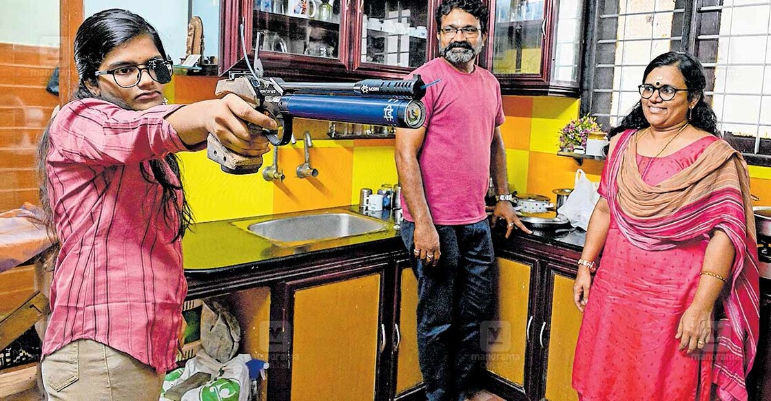 athulya-air-pistol-gold സംസ്ഥാന സ്കൂൾ കായികമേള ഷൂട്ടിങ് സീനിയർ പെൺകുട്ടികളുടെ എയർ പിസ്റ്റളിൽ സ്വർണം നേടിയ അതുല്യ എസ്. നായർ തൃക്കാക്കരയിലെ വീട്ടിൽ പരിശീലനം നടത്തുന്നു. വീട്ടിലെ അടുക്കളയിൽ കൃത്യമായ അകലം സെറ്റ് ചെയ്താണ് അതുല്യയുടെ പരിശീലനം. അച്ഛൻ സതീഷ് കുമാർ, അമ്മ ലത എന്നിവർ സമീപം. ചിത്രം: ഇ.വി ശ്രീകുമാർ / മനോരമ