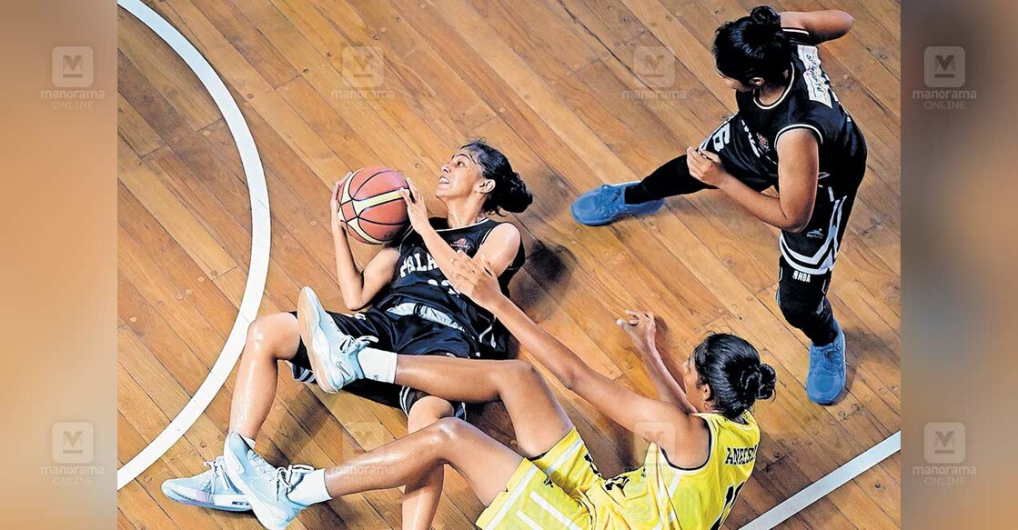 state-senior-basketball-champions സംസ്ഥാന സീനിയർ ബാസ്കറ്റ്ബോൾ വനിതാ ഫൈനൽ മത്സരത്തിനിടെ വീണുപോയ പാലക്കാടിന്റെ ചിപ്പിയിൽനിന്ന് (ഇടത്) പന്ത് പിടിച്ചെടുക്കാൻ ശ്രമിക്കുന്ന തിരുവനന്തപുരത്തിന്റെ അനീഷ. ചിത്രം: അരുൺ ശ്രീധർ / മനോരമ