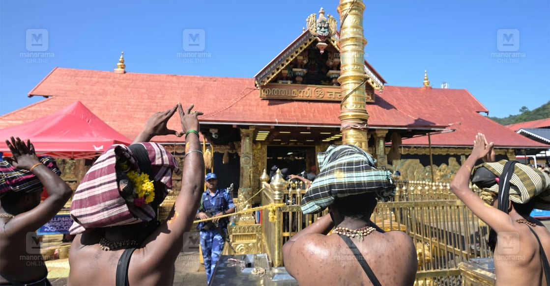 പതിനെട്ടാംപടി കയറി കൊടിമരച്ചുവട്ടിൽ എത്തിയ തീർഥാടകർ തൊഴുകൈകളോടെ പ്രാർഥിക്കുന്നു. ചിത്രം: അരുൺ ജോൺ / മനോരമ
