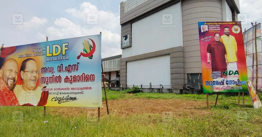 ഇരിങ്ങാലക്കുടയില്‍ അന്തരിച്ച നടൻ ഇന്നസെന്റിനൊപ്പമുള്ള ചിത്രമടങ്ങിയ ബോർഡ് ഉയർത്തിയിരിക്കുന്ന എൽഡിഎഫ്, എൻഡിഎ സ്ഥാനാർഥികൾ.