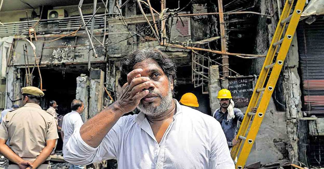 delhi-hospital-fire-child-death-father ഹൃദയമുരുകി: കിഴക്കൻ ഡൽഹിയിലെ വിവേക് വിഹാറിൽ തീപിടിത്തത്തിൽ മരിച്ച നവജാത ശിശുക്കളിലൊരാളുടെ പിതാവായ അഞ്ജർ ചൗധരി കത്തിനശിച്ച ആശുപത്രിക്കെട്ടിടത്തിനു മുന്നിൽ. ചിത്രം: പിടിഐ