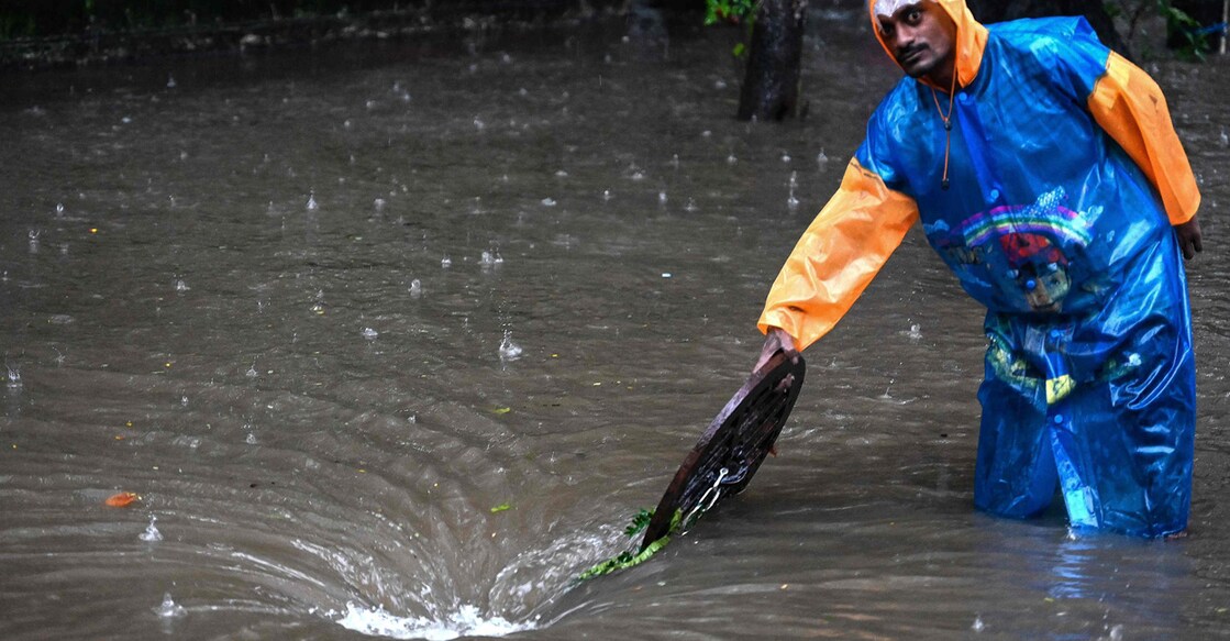 മുംബൈയിൽ കനത്ത മഴയെ തുടർന്നുണ്ടായ വെള്ളക്കെട്ടിനെ തുടർന്നു വാഹനങ്ങൾക്ക് നിർദേശങ്ങൾ നൽകുന്ന തൊഴിലാളി (Photo by Sujit JAISWAL / AFP)