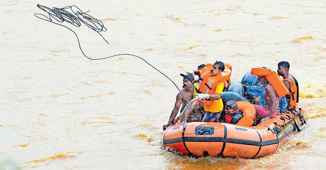 ചാലിയാറിലൂടെ ഒഴുകിയെത്തി തരിപ്പപ്പൊട്ടി തീരത്തടിഞ്ഞ മൃതദേഹങ്ങൾ വീണ്ടെടുക്കാനായി അഗ്നിരക്ഷാസേനയുടെ ഡിങ്കി ബോട്ടിൽ പോകുന്നവർ.