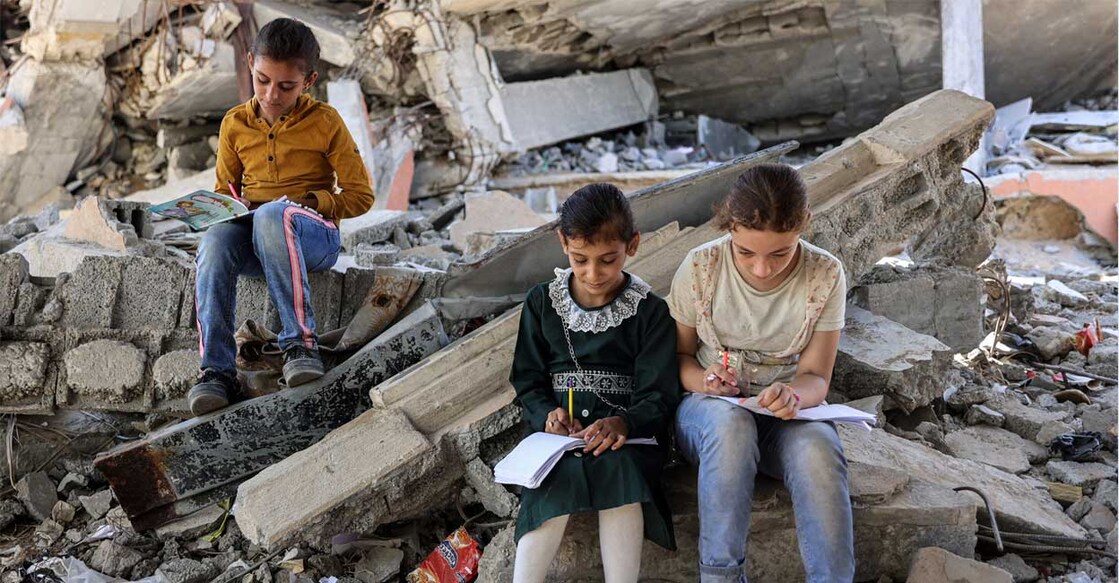 israel-attack-gaza-students ഗാസയിൽ ഇസ്രയേൽ ബോംബാക്രമണത്തിൽ തകർന്ന കെട്ടിടത്തിനു സമീപം പഠിക്കുന്ന കുട്ടികൾ. (Photo by Omar AL-QATTAA / AFP)