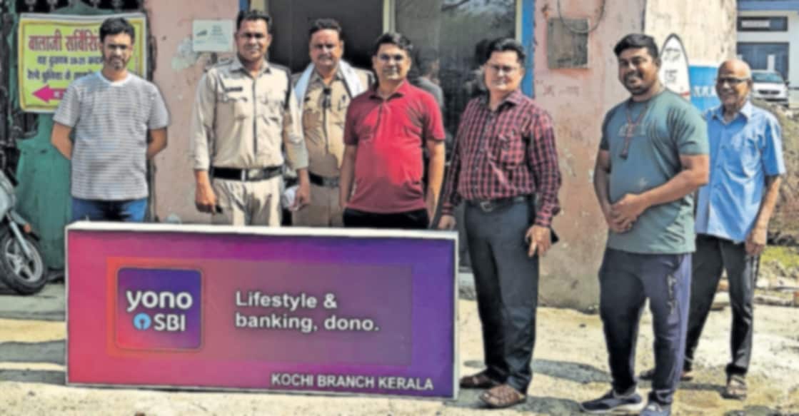 bank-fraud മധ്യപ്രദേശിൽ കണ്ടെത്തിയ വ്യാജ ബാങ്കിൽ പൊലീസും ഉദ്യോഗസ്ഥരും പരിശോധന നടത്തിയപ്പോൾ. പിന്നിൽ കാണുന്ന കെട്ടിടത്തിലാണു വ്യാജ ബാങ്ക് പ്രവർത്തിച്ചിരുന്നത്. ബാങ്കിന്റെ ബോർഡാണ് ഇളക്കി താഴെവച്ചിരിക്കുന്നത്.