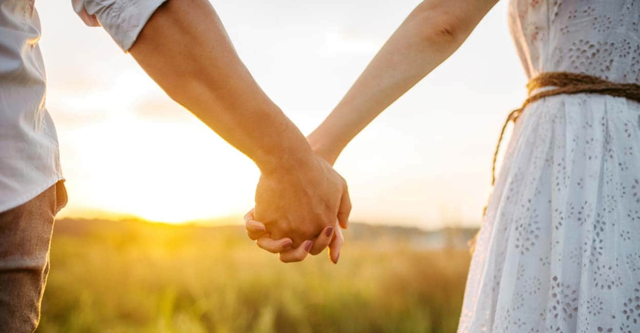 couple-hold-hands-green-field