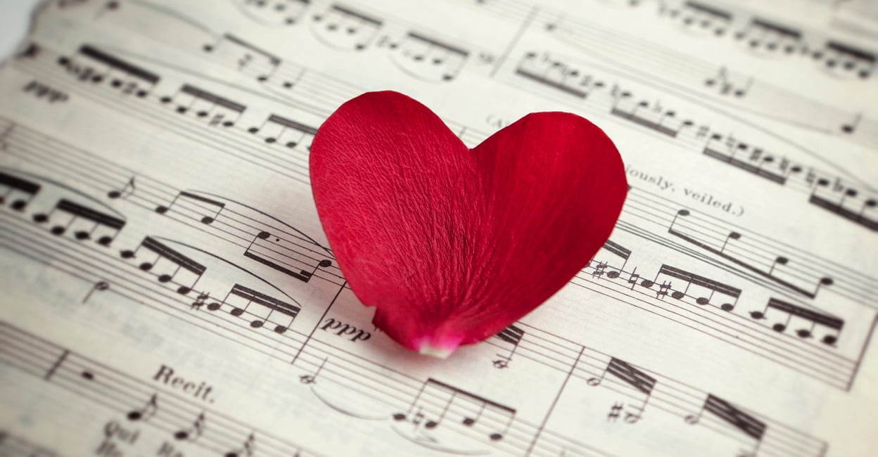 Heart shaped rose petal on music sheet. Love song concept. Music sheet is vintage from Aida by Giuseppe Verdi.