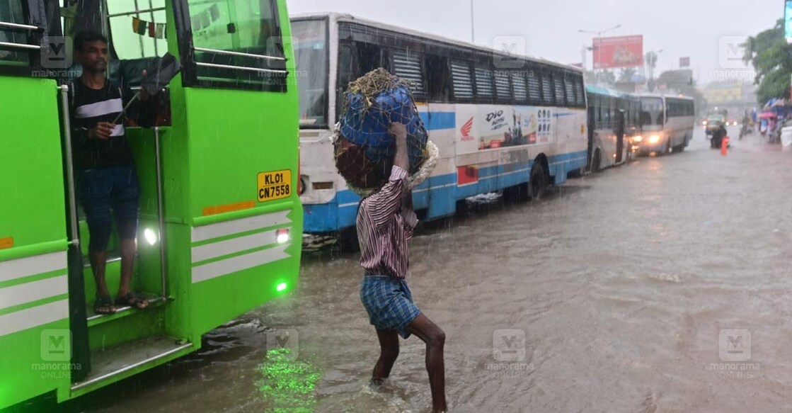 മഴയത്ത് തിരുവനന്തപുരം കിഴക്കേക്കോട്ടയിലെ വെള്ളക്കെട്ടിലേക്ക് ബസിൽ വന്നിറങ്ങുന്നവർ. ചിത്രം : റിങ്കുരാജ് മട്ടാഞ്ചേരിയിൽ ∙ മനോരമ 
